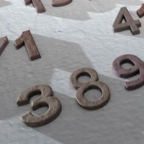 Dreidimensionale Zahlen liegen verstreut auf rauer Oberfläche.