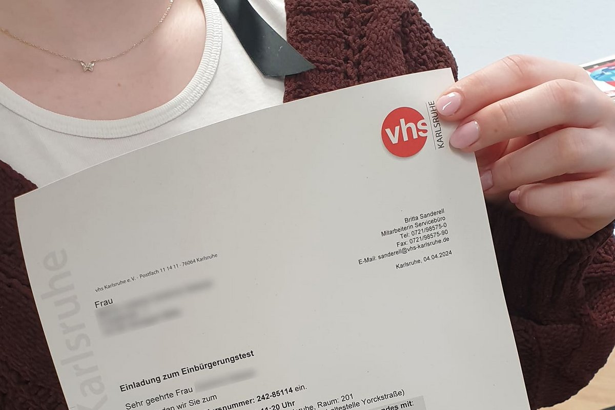 Person hält die Einladung zum Einbürgerungstest in den Händen.